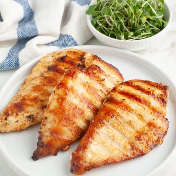 Plate of grilled chicken and a bowl of greens.