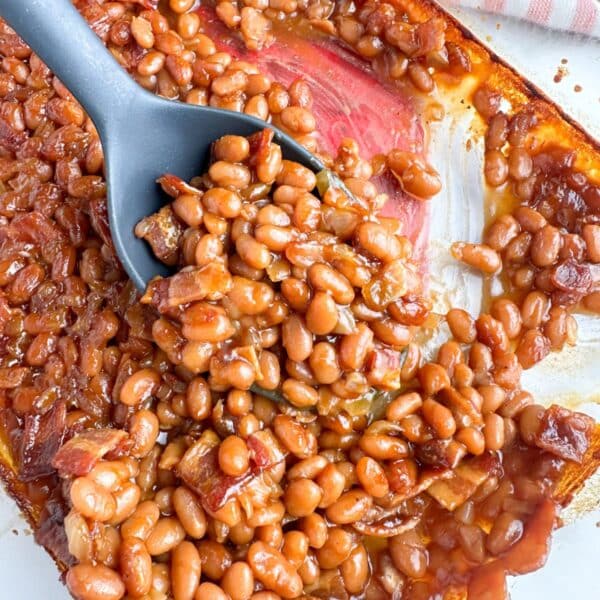 Baking dish with baked beans and spoon.