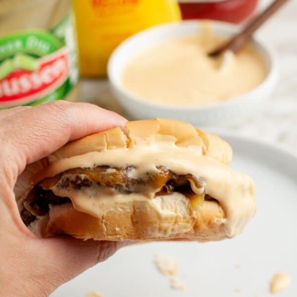 Hand holding a cheeseburger with smashburger sauce.