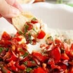 Hand holding bread topped with bruschetta dip.