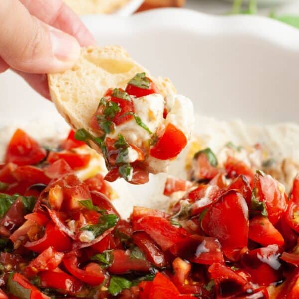 Hand holding bread topped with bruschetta dip.