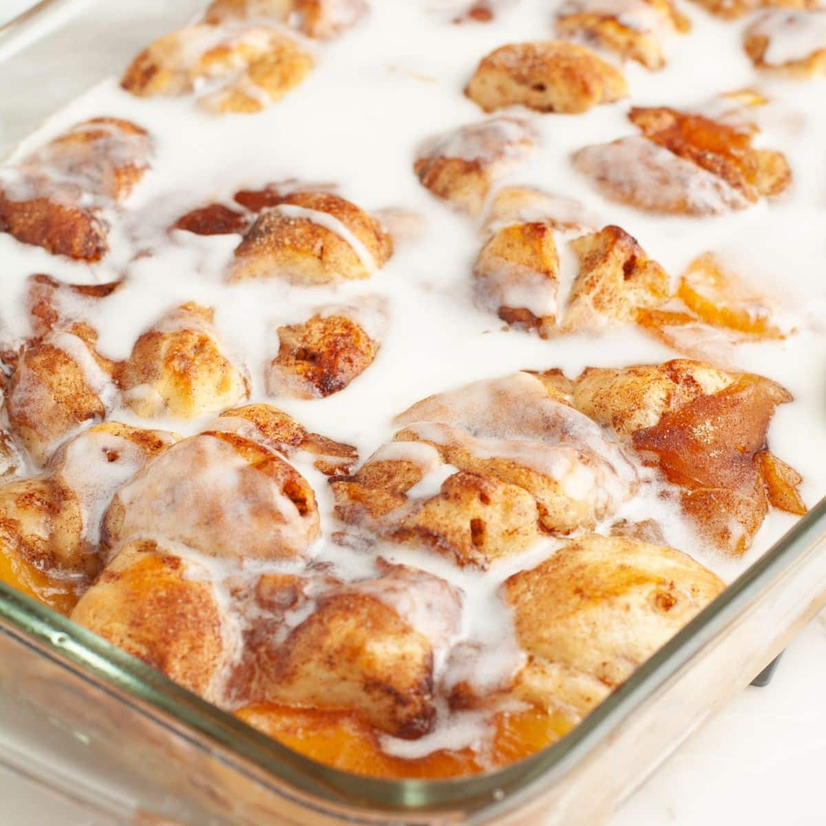 Baking dish with cinnamon roll peach cobbler.