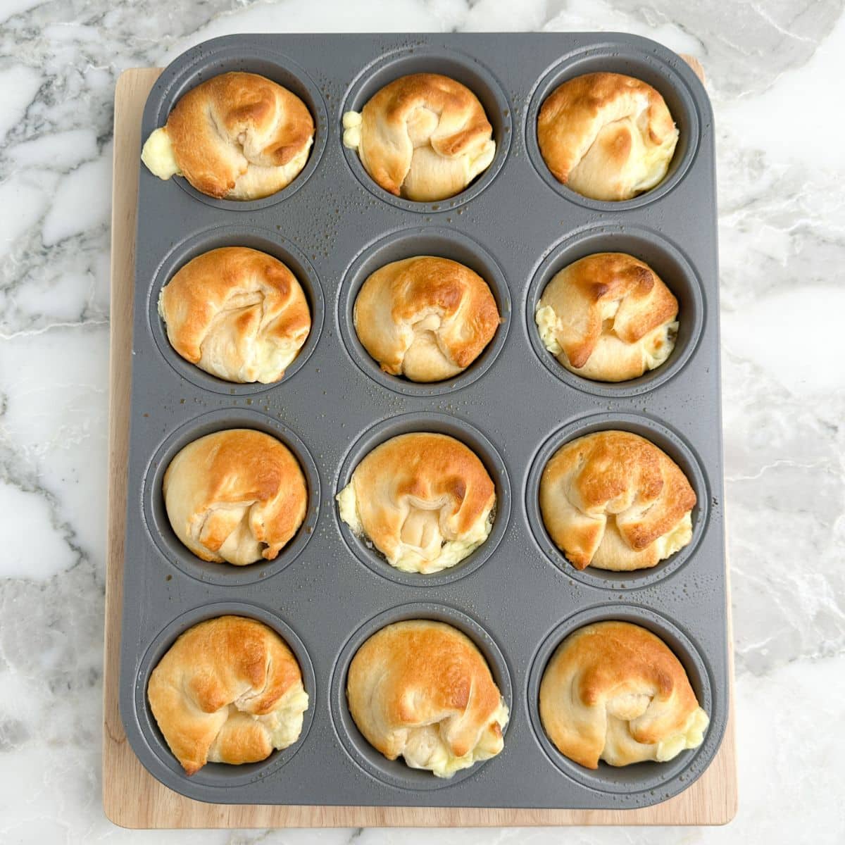 Muffin tin with cooked peach crescent cheesecakes.
