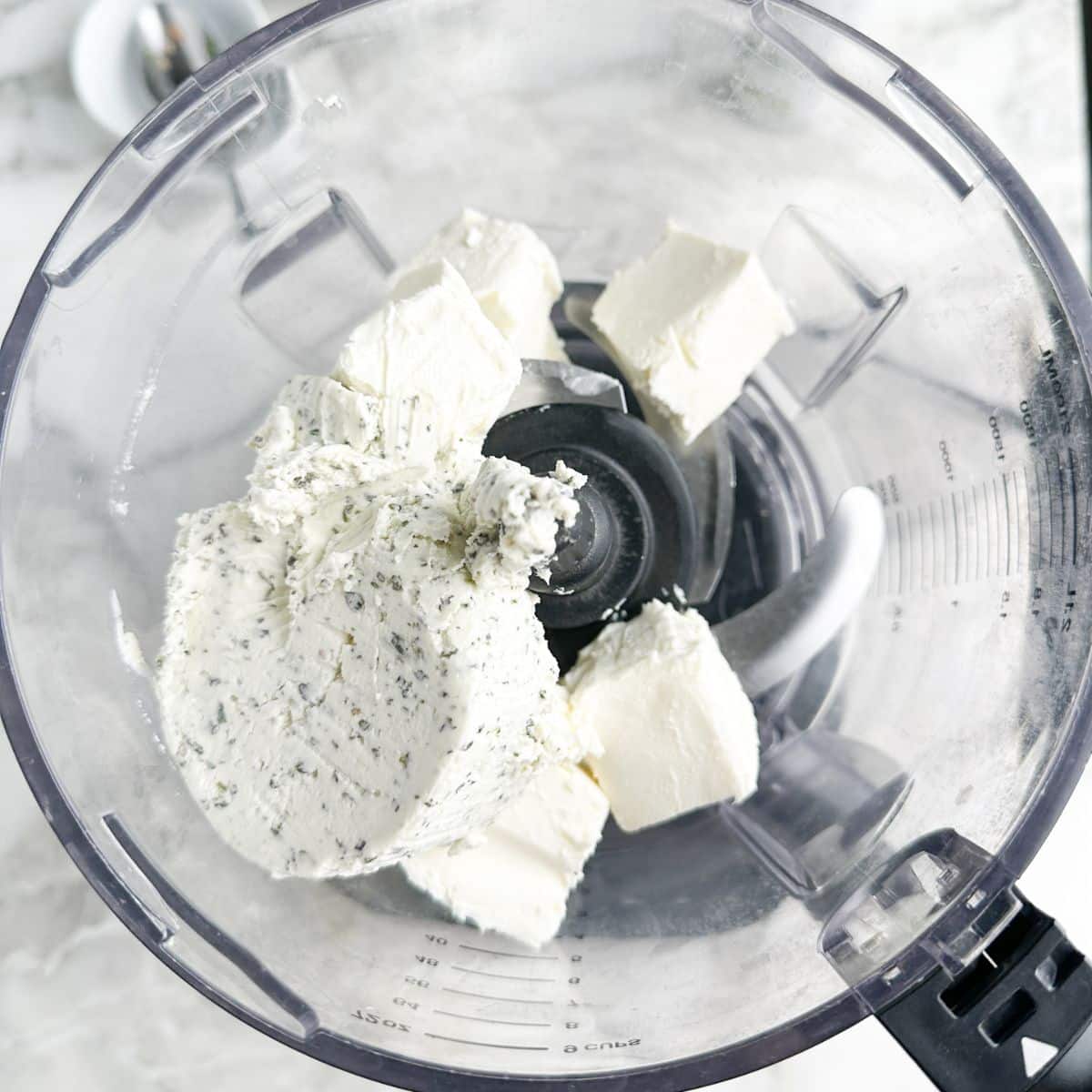 Food processor with cream cheese and Boursin cheese.