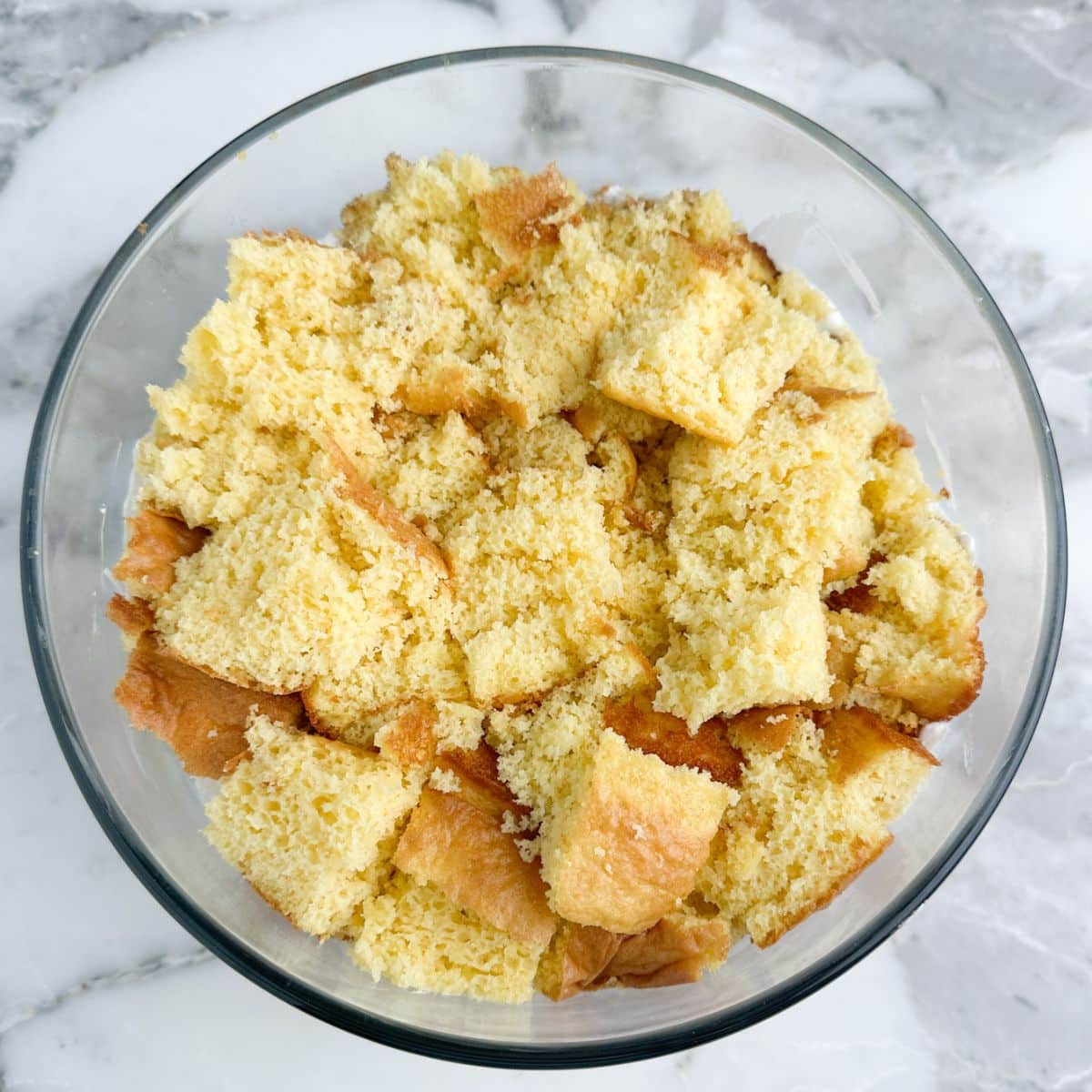 Glass bowl with pieces of baked yellow cake.
