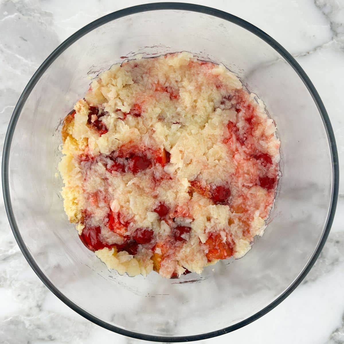 Glass bowl with cake, cherry pie filling, and crushed pineapple.