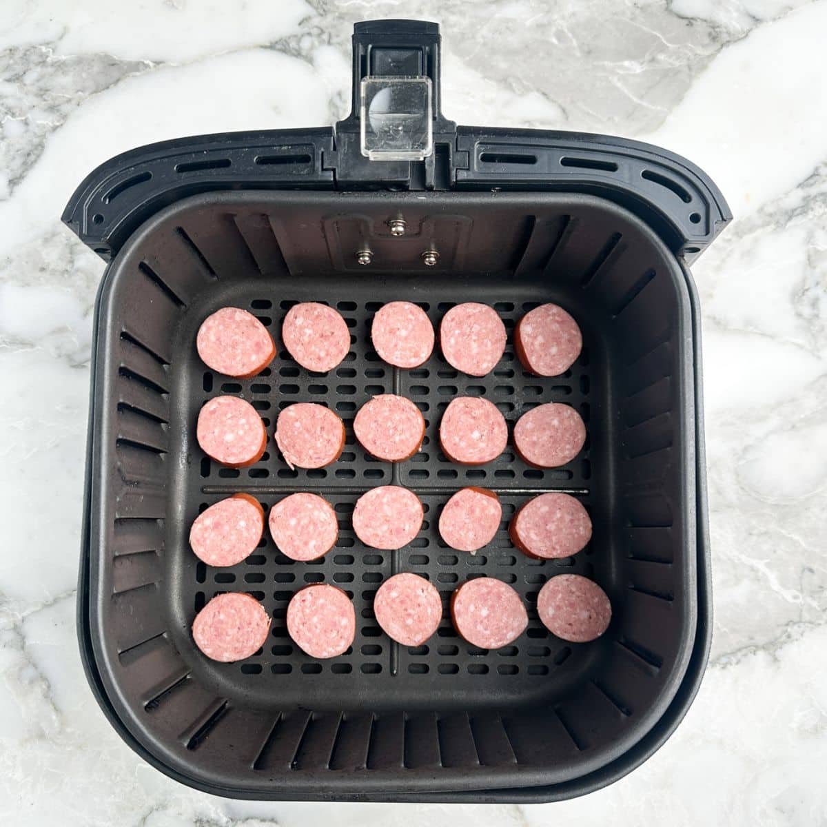 Air fryer basket with sliced kielbasa. 