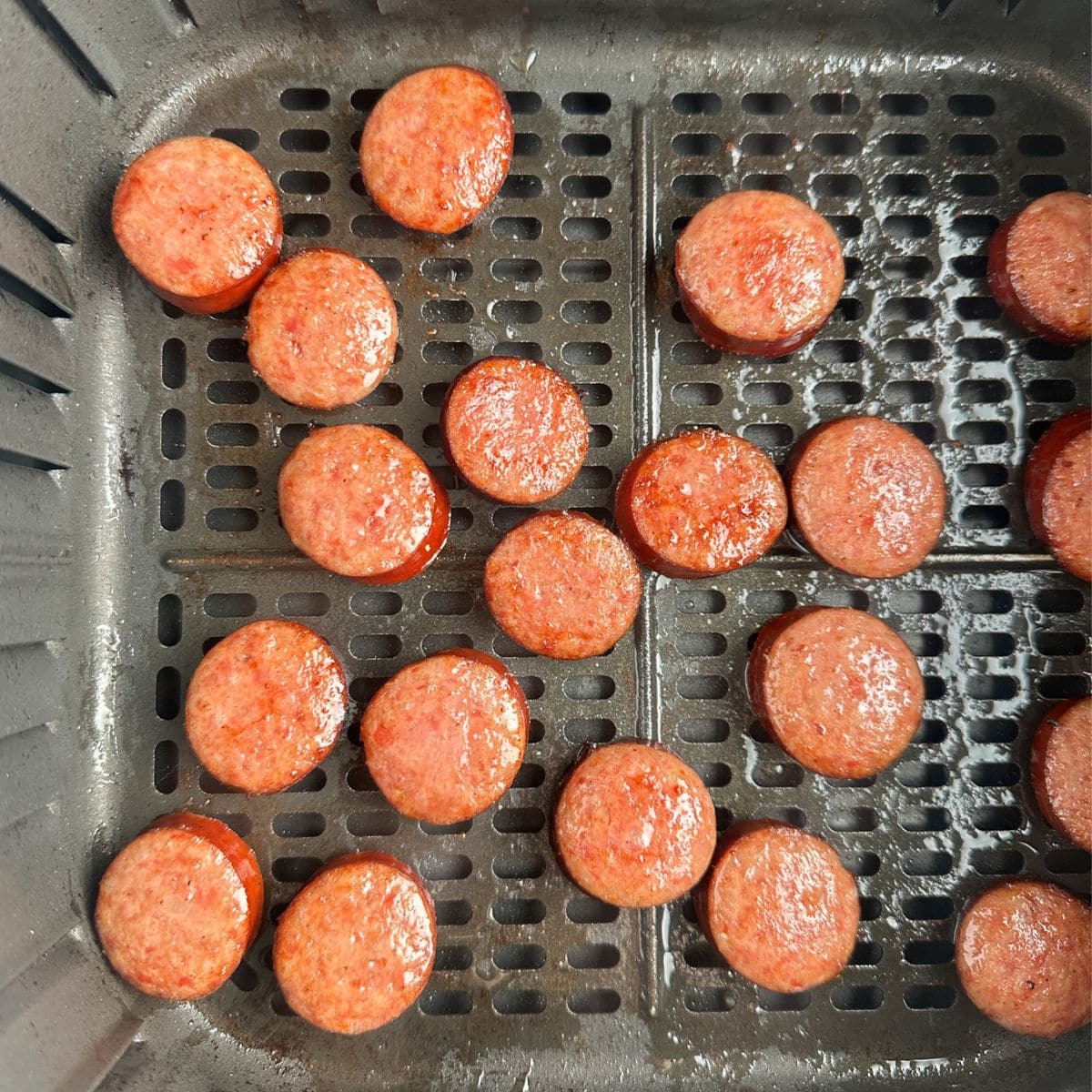 Air fryer basket with cooked kielbasa. 