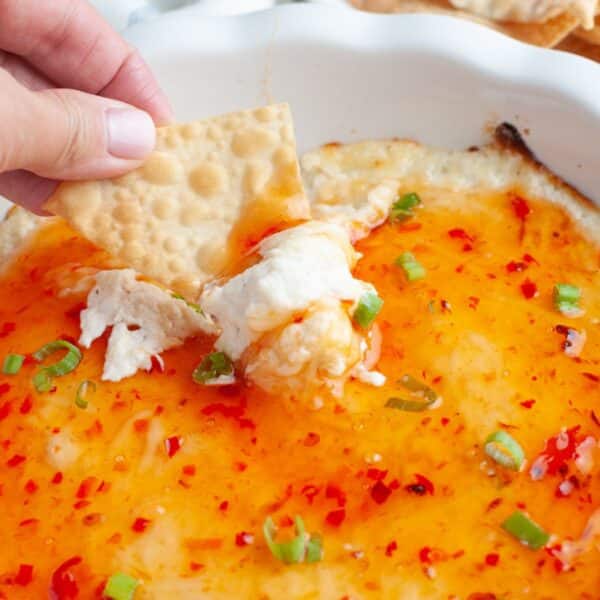 Baking dish with crab rangoon dip and chip dipping into it.