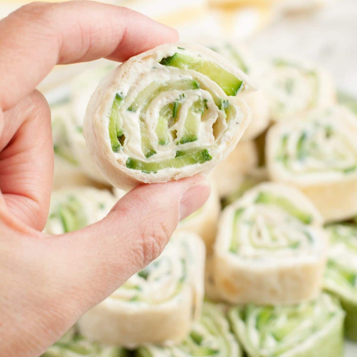 Hand holding a cucumber pinwheel. 