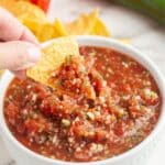 Bowl of salsa with a tortilla chip dipping into it.