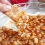 Hand holding a cinnamon cracker with apple pie dip.