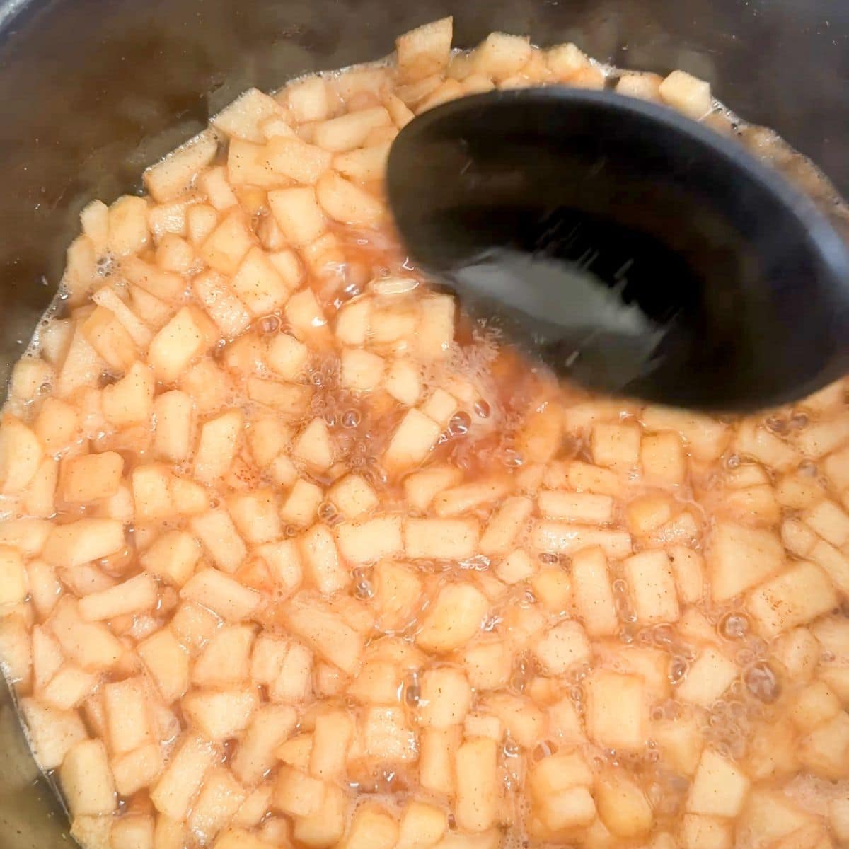 Pot with apple pie mixture and a spoon.