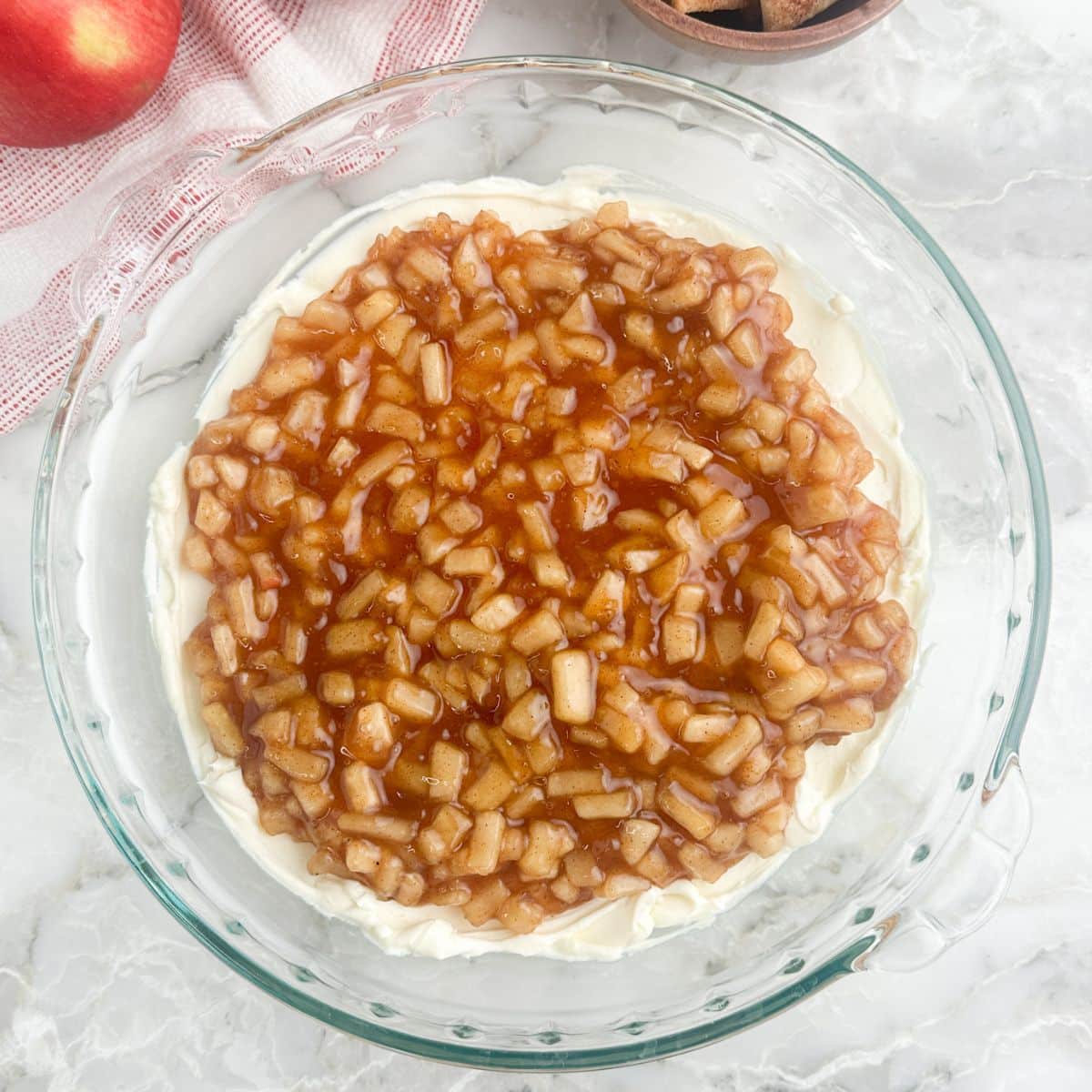 Pie dish with cream cheese and apple pie filling.