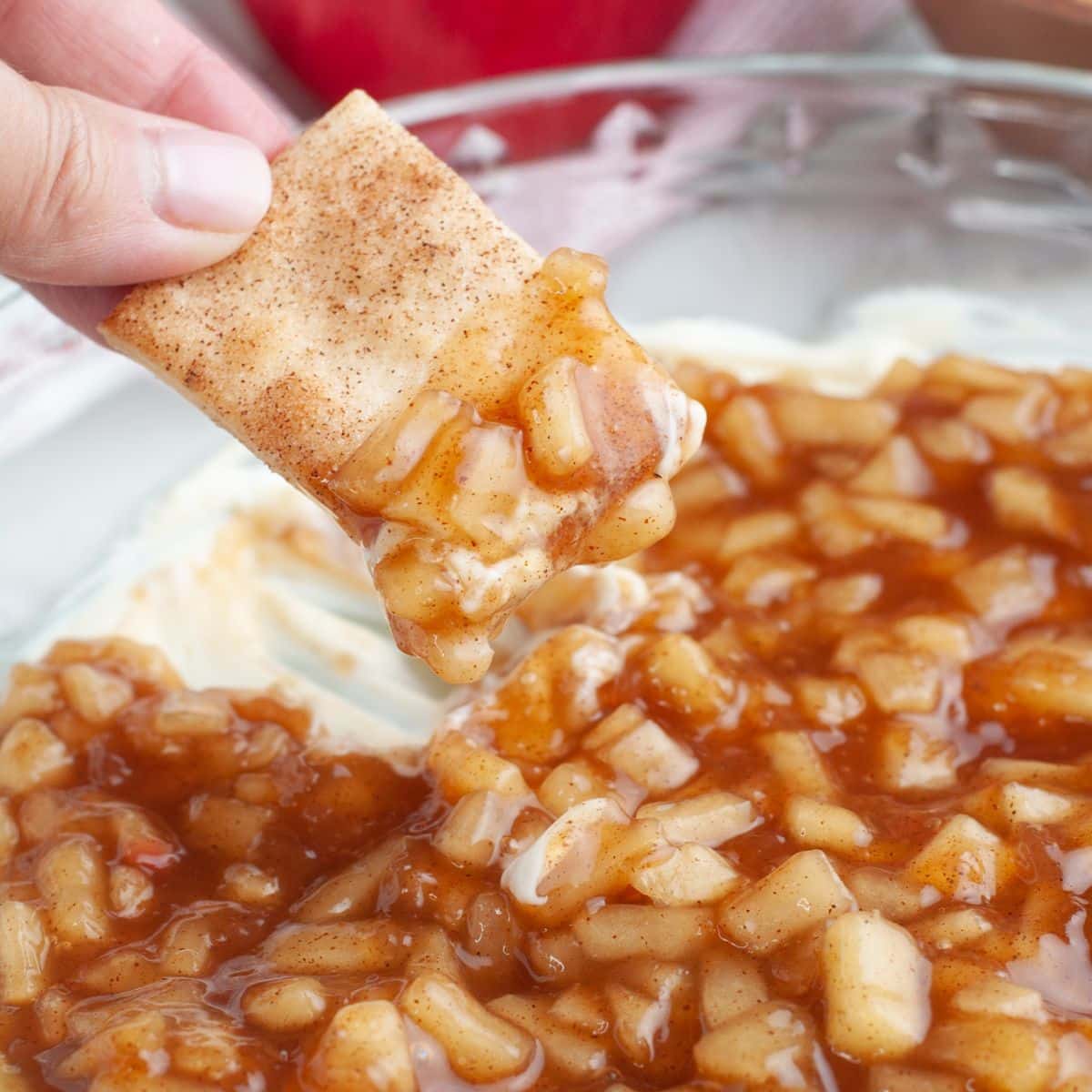 Hand holding a cinnamon cracker with apple pie dip. 