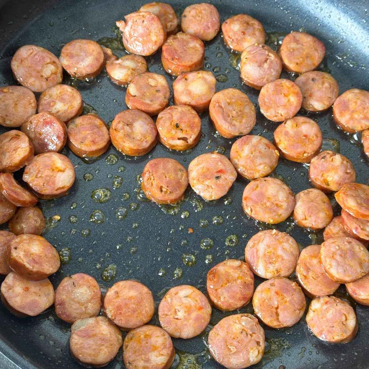 Skillet with sliced andouille sausage.