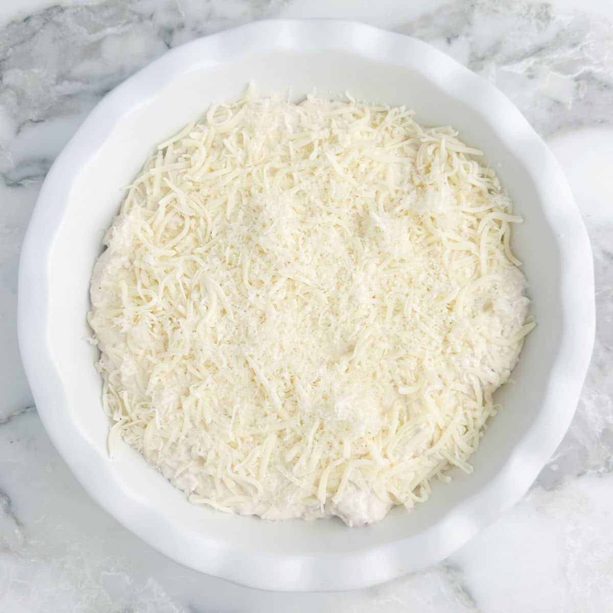 Baking dish with unbaked chicken alfredo dip. 