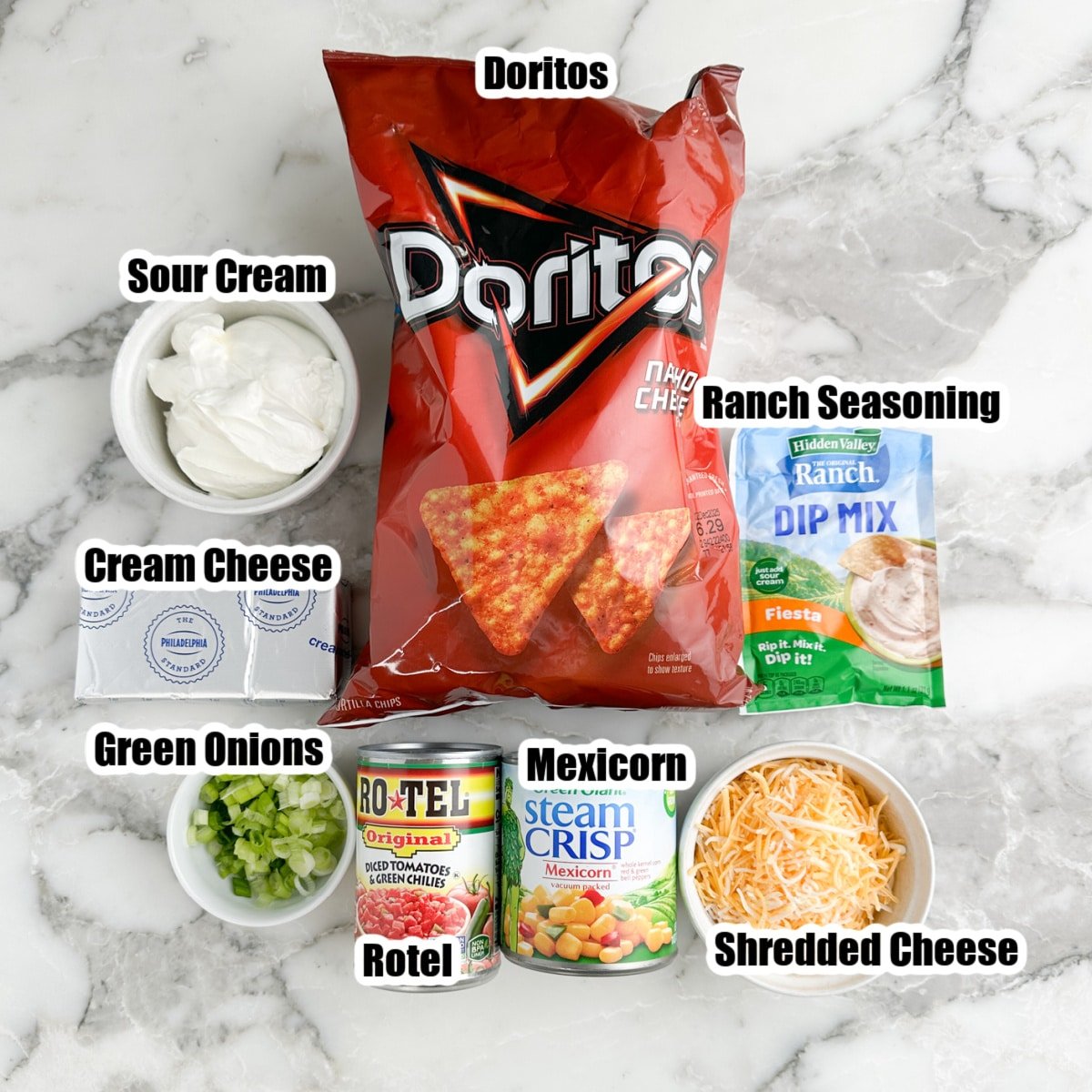 Bag of Doritos chips, ranch seasoning, bowl of sour cream, cheese, onions, Mexicorn, and Rotel. 