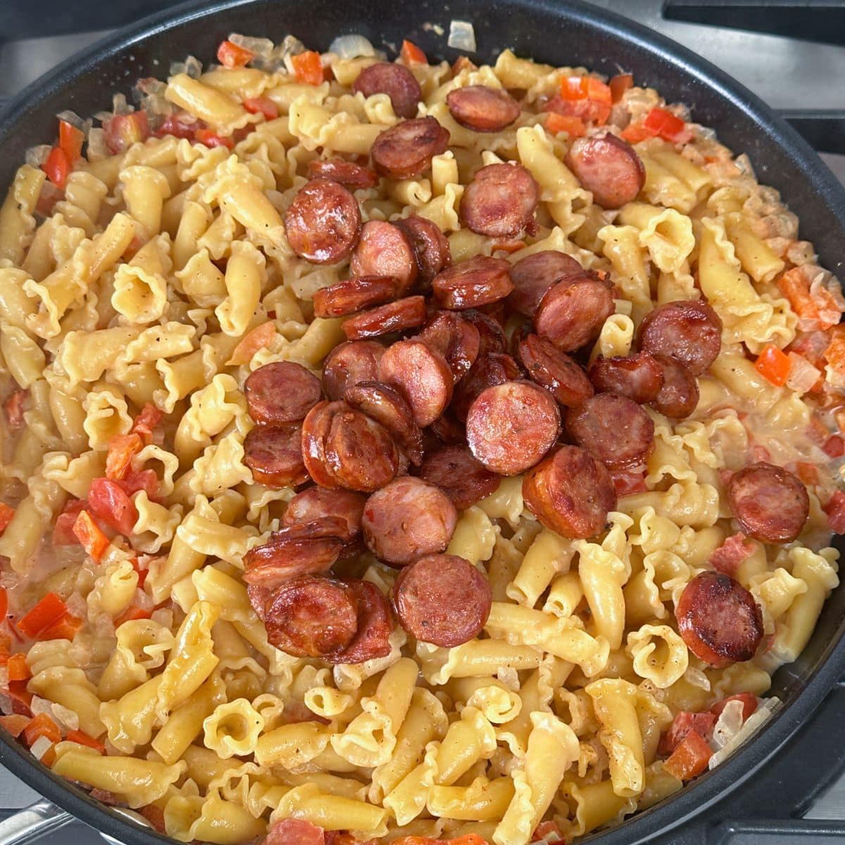 Skillet with pasta and cooked andouille sausage. 