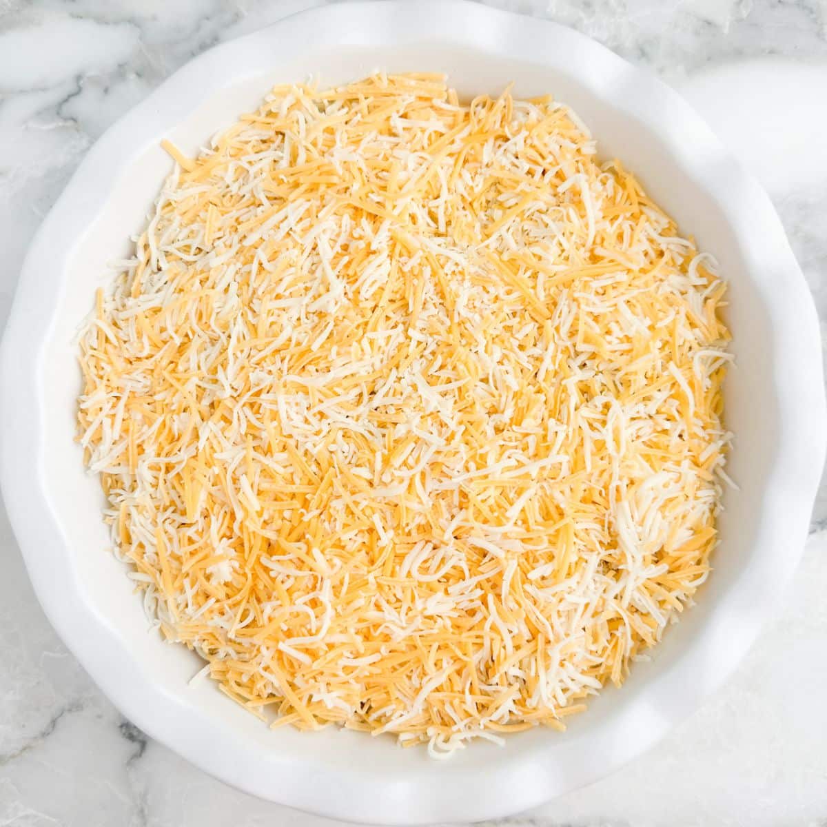 Pie dish with dip topped with shredded cheese.