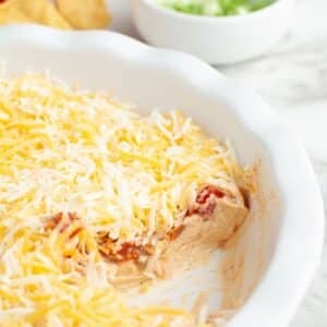 Pie dish with layered salsa dip that is topped with cheese.