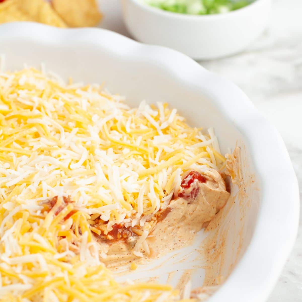 Pie dish with layered salsa dip that is topped with cheese. 