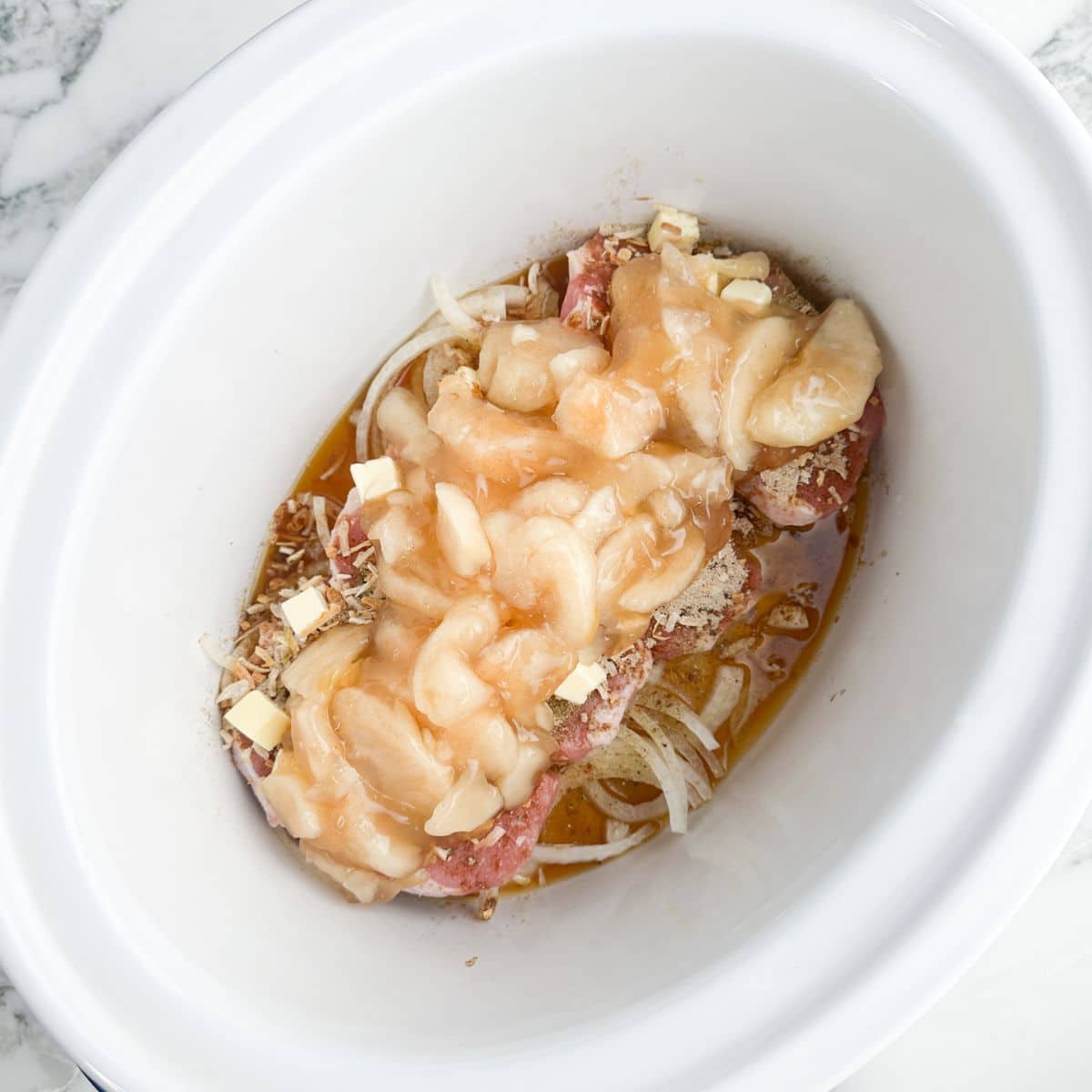 Slow cooker with pork chops and apple pie filling.