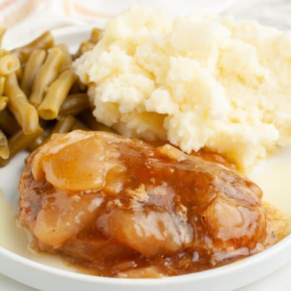 Plate with apple pie pork chop, mashed potatoes, and green beans.
