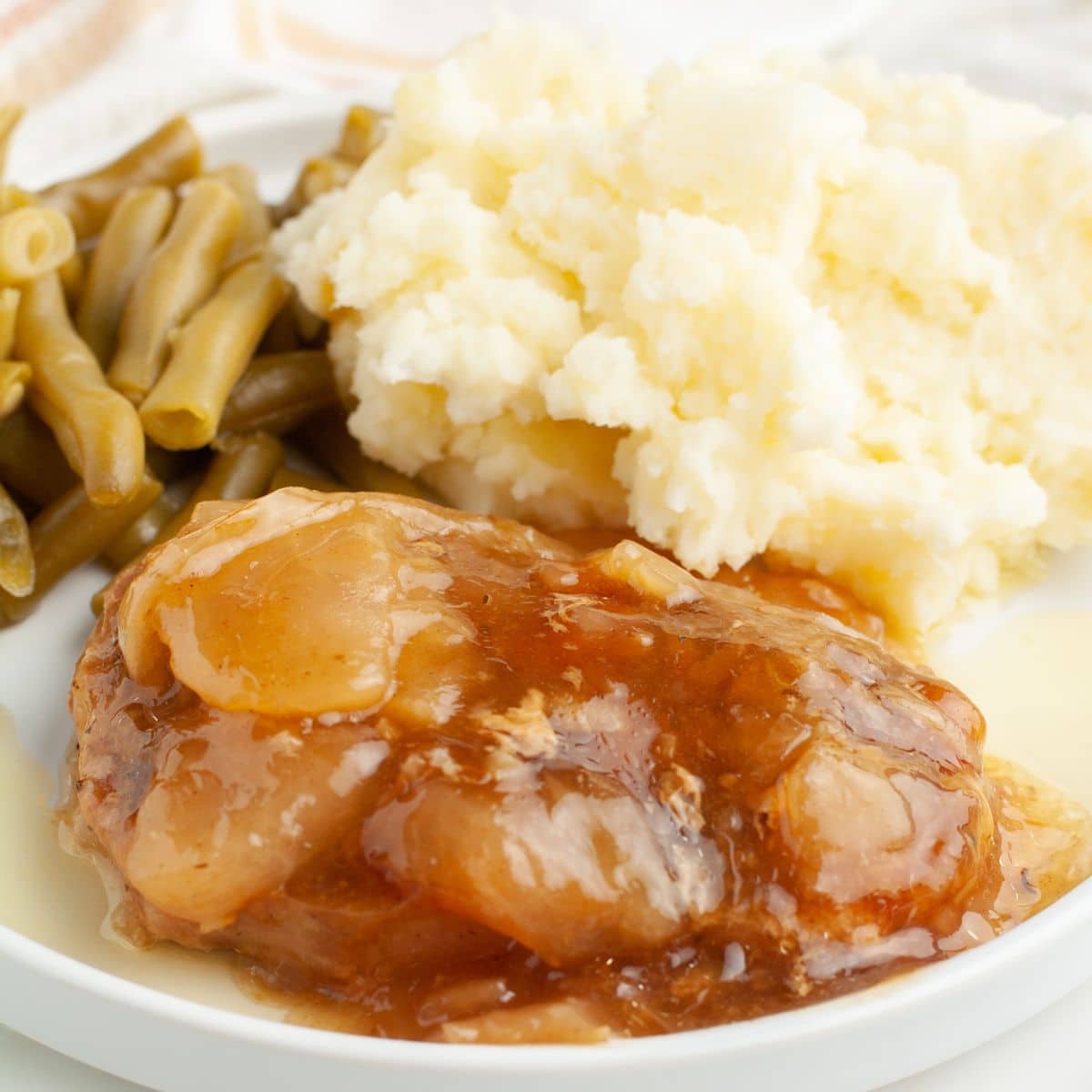 Plate with apple pie pork chop, mashed potatoes, and green beans.