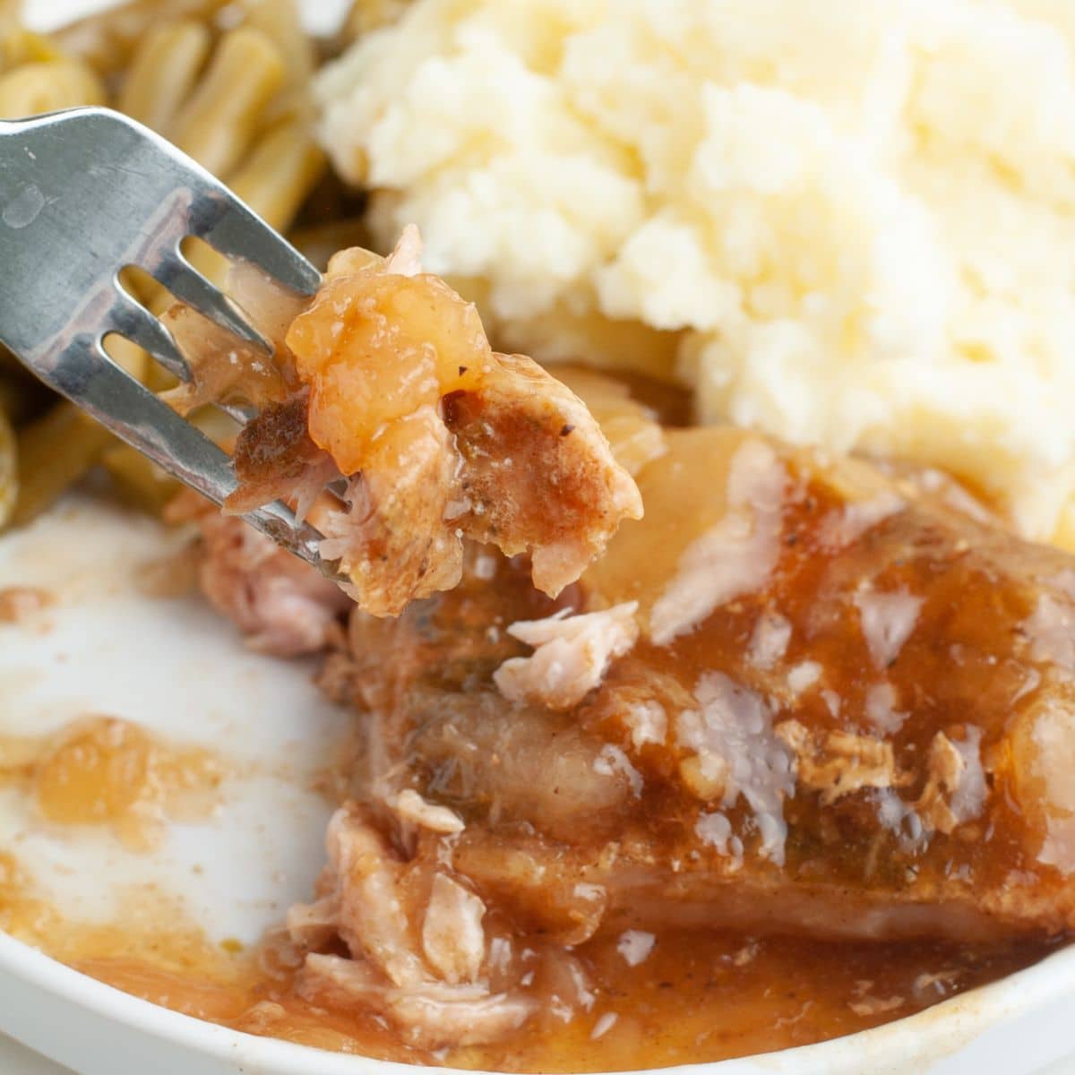 Plate with fork picking up pork chops and apples.