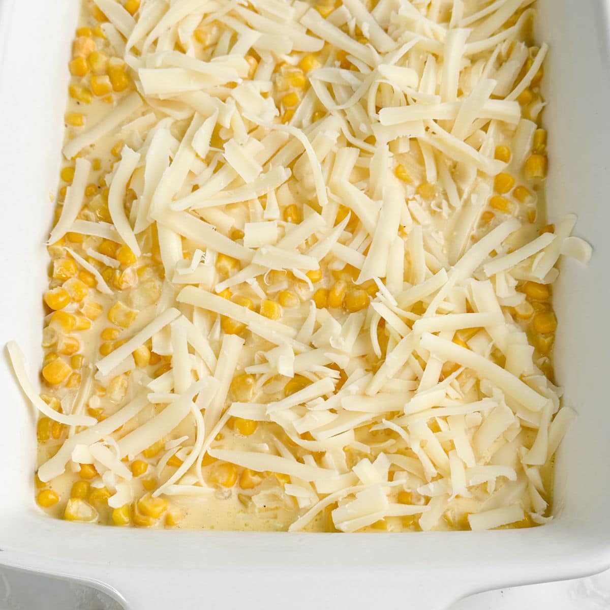 Casserole dish with corn casserole topped with swiss cheese.