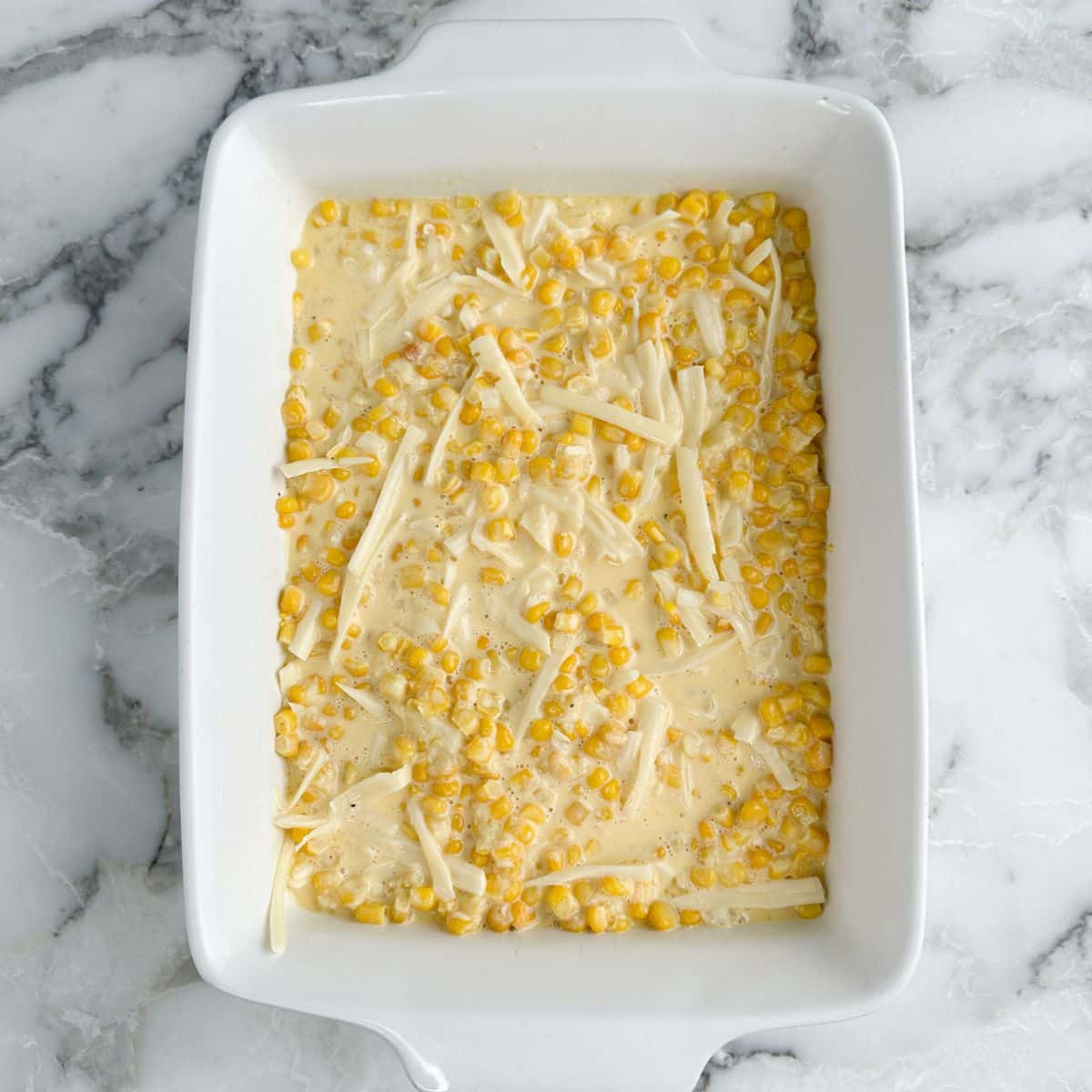 Casserole dish with unbaked corn casserole.