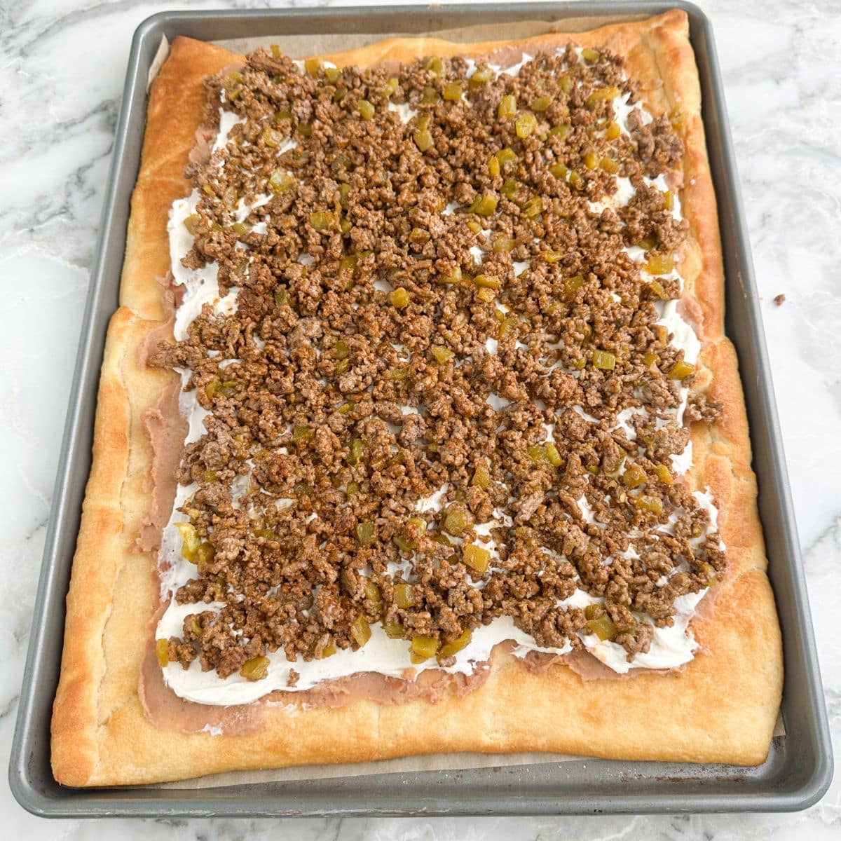 Crescent roll dough topped with beans, sour cream, and ground beef. 