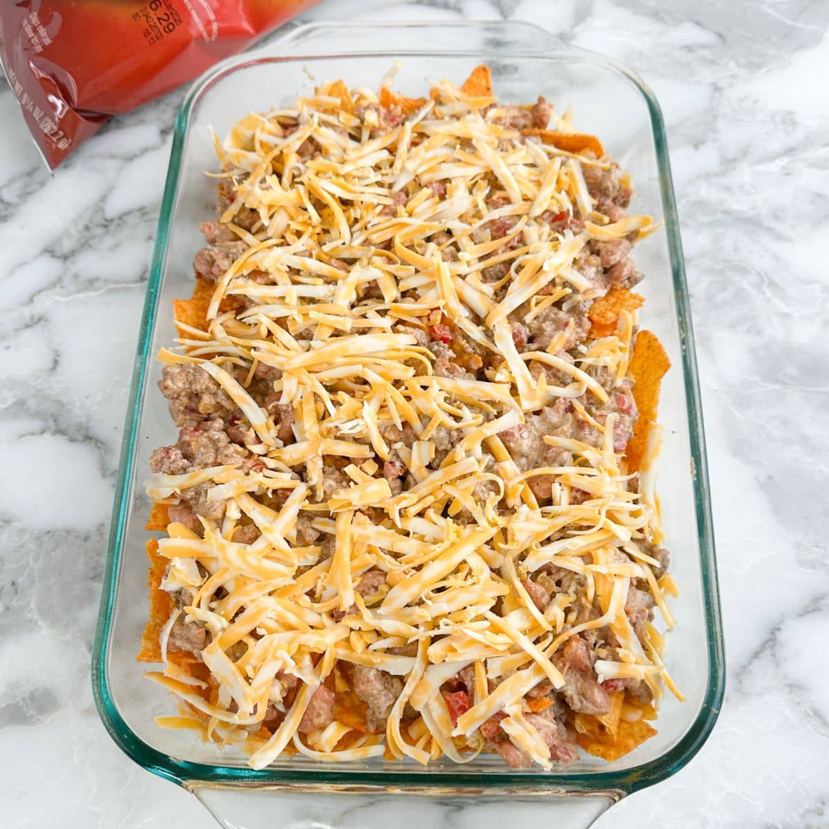 Casserole dish with Doritos chips, ground beef, and shredded cheese.