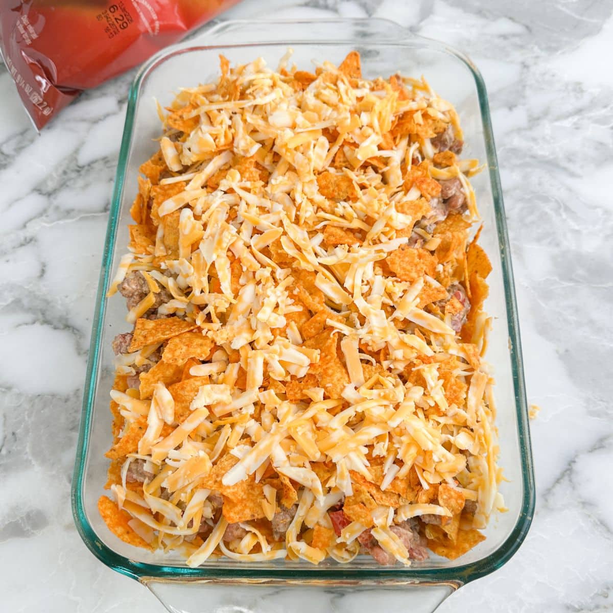 Casserole dish with unbaked Doritos casserole.