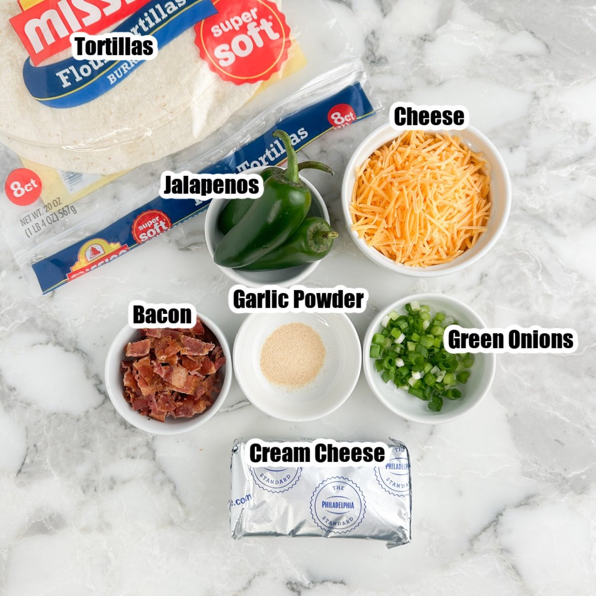 Tortillas, bowls of shredded cheese, jalapenos, bacon, green onions, and cream cheese.
