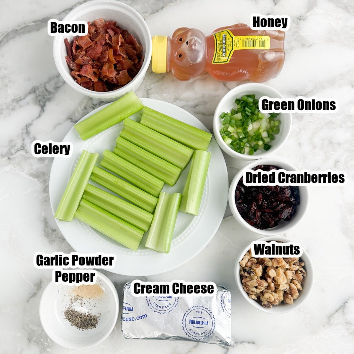 Celery stalks, bowls of bacon, nuts, green onions, honey, and cream cheese.