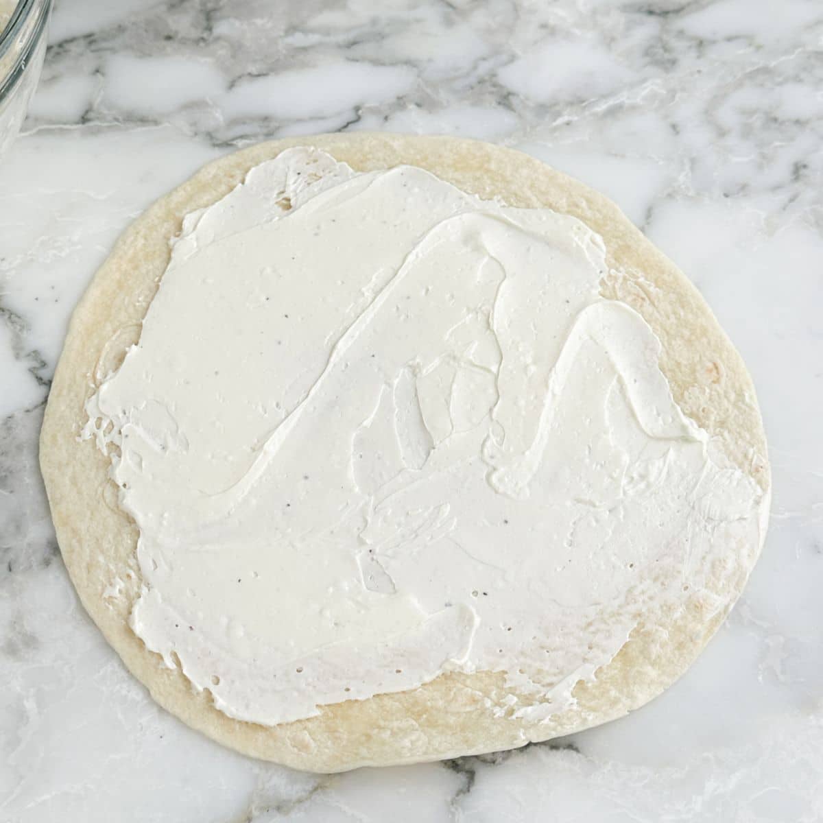 Tortilla with cream cheese spread on top.