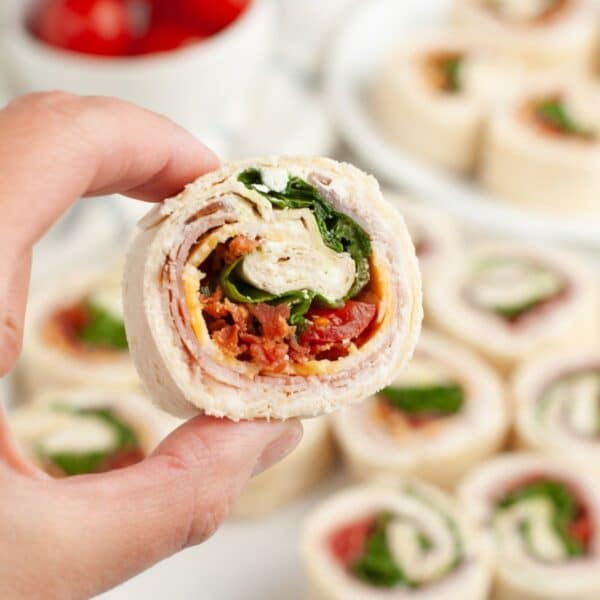 Hand holding a club sandwich pinwheel.