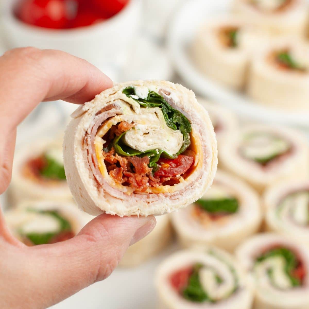 Hand holding a club sandwich pinwheel.
