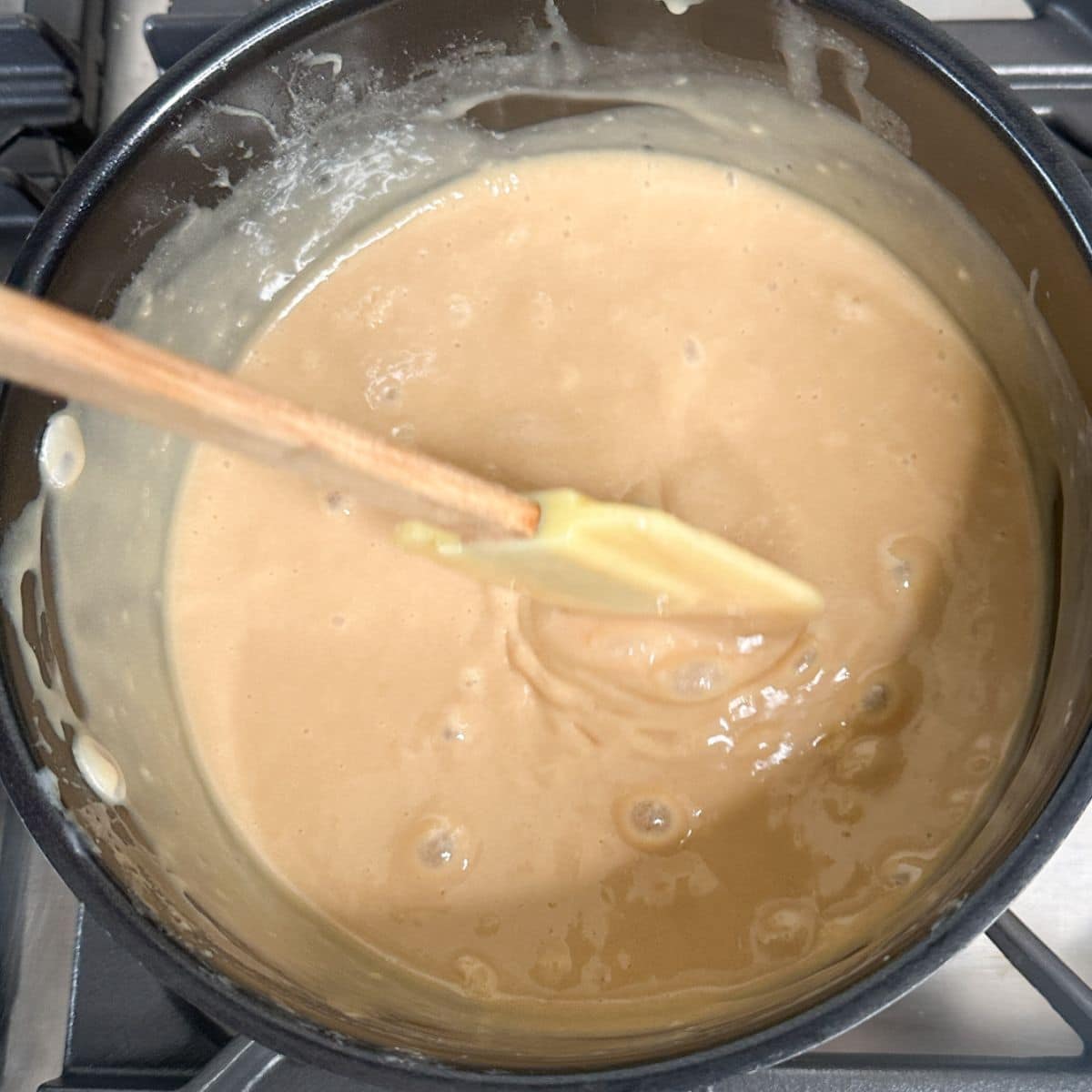 Saucepan with caramel sauce and spatula. 