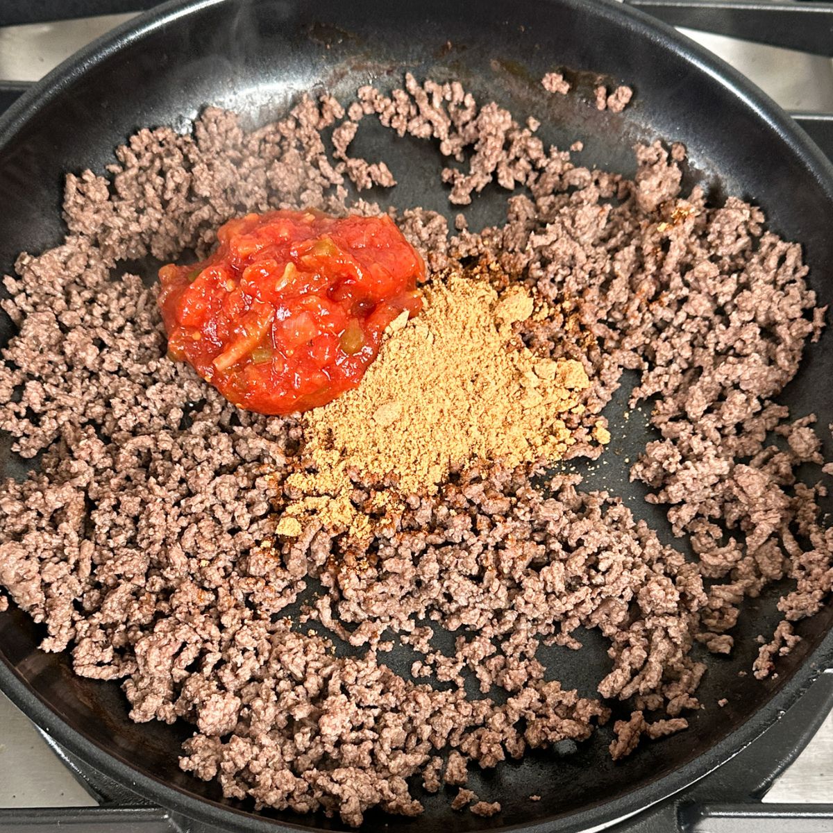 Skillet with ground beef with taco seasonings and salsa.