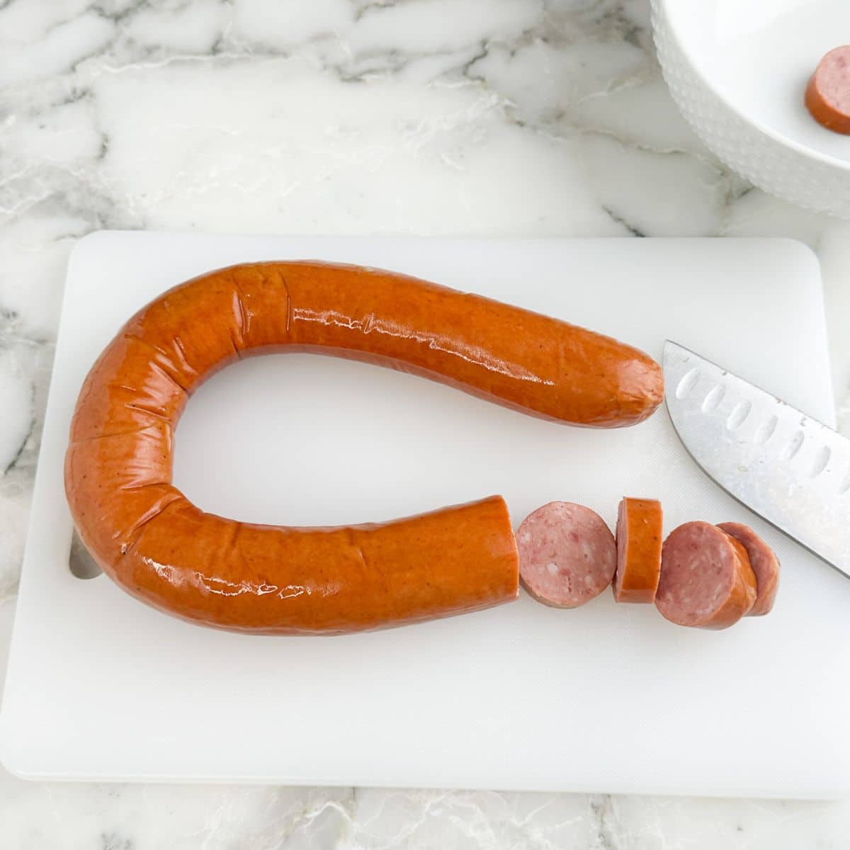 Kielbasa on a cutting board being sliced.
