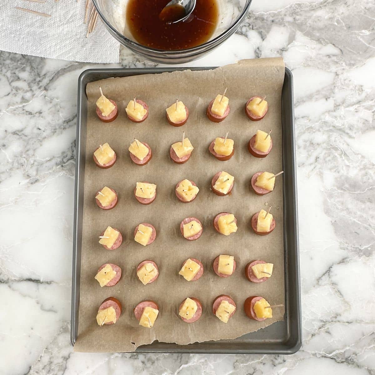 Baking sheet with kielbasa pineapple bites.
