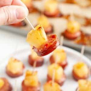 Hand holding a pineapple kielbasa bite.