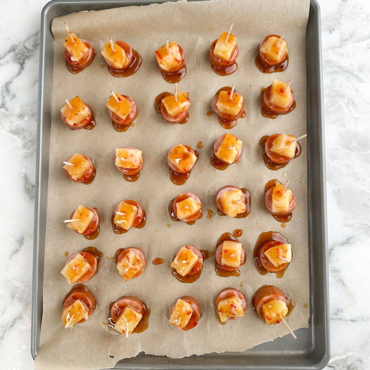 Baking sheet with pineapple kielbasa bites.