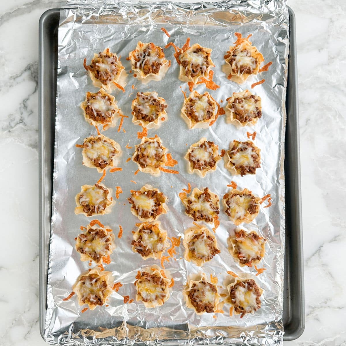 Baking pan with taco bites with melted cheese.