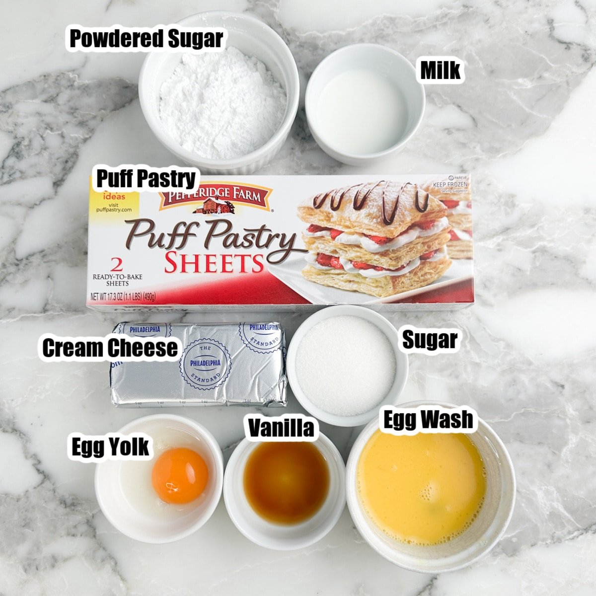 Box of puff pastry, bowl of sugar, powdered sugar, milk, egg, vanilla, and cream cheese.