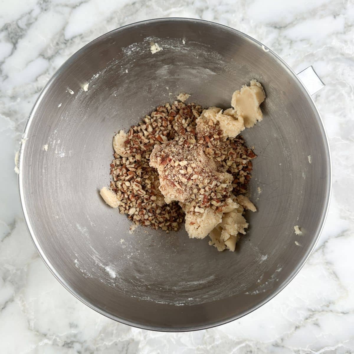 Mixing bowl with cookie dough and chopped pecans. 