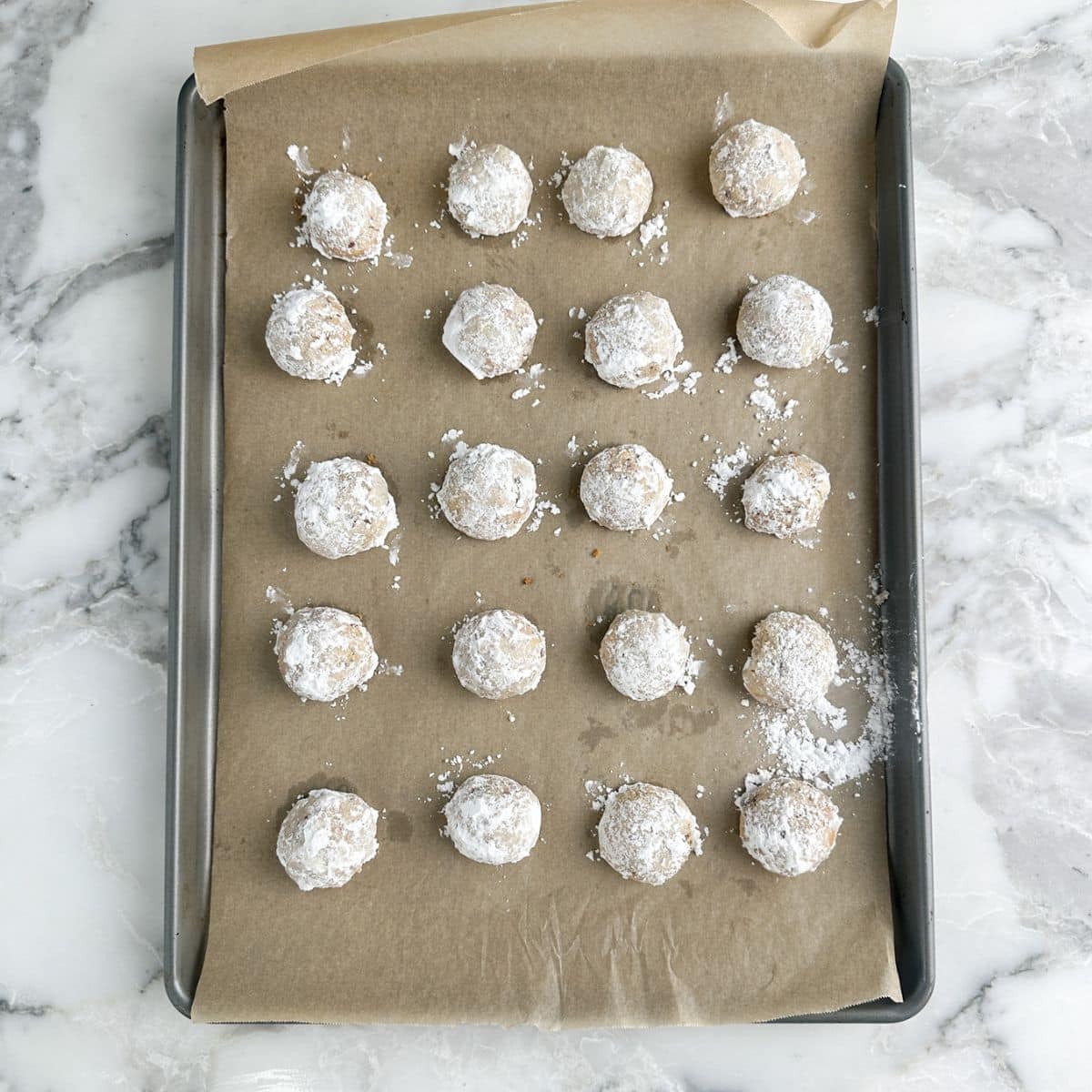 Baking sheet with powdered sugar pecan balls. 